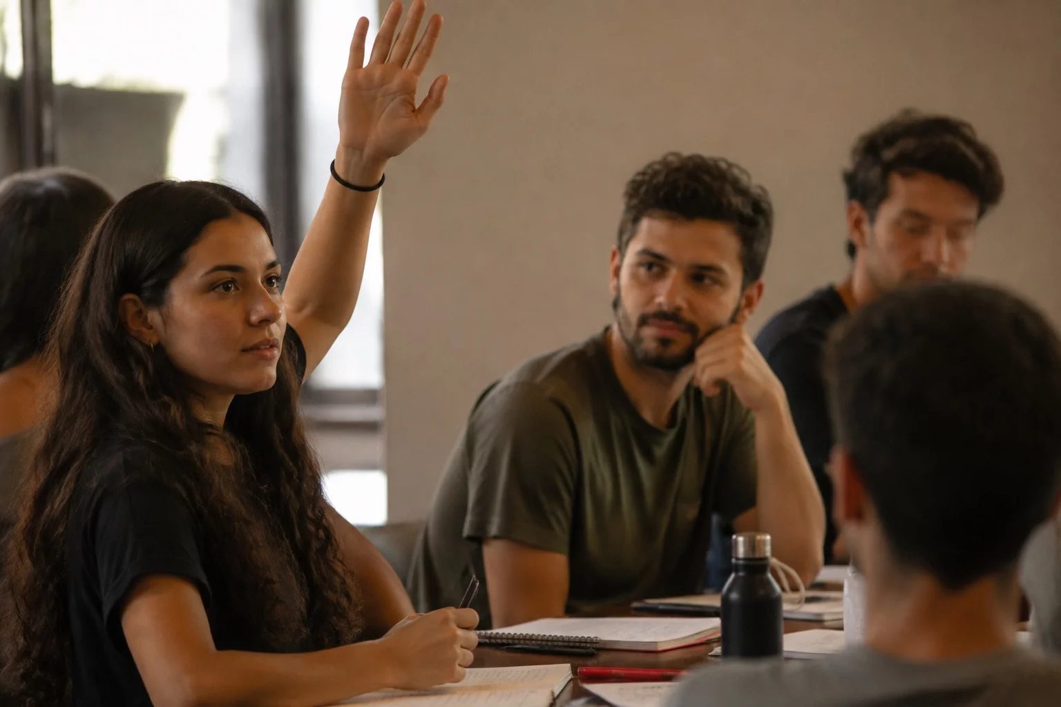 Estudante levantando a mão em uma mesa de seminário coberta de anotações
