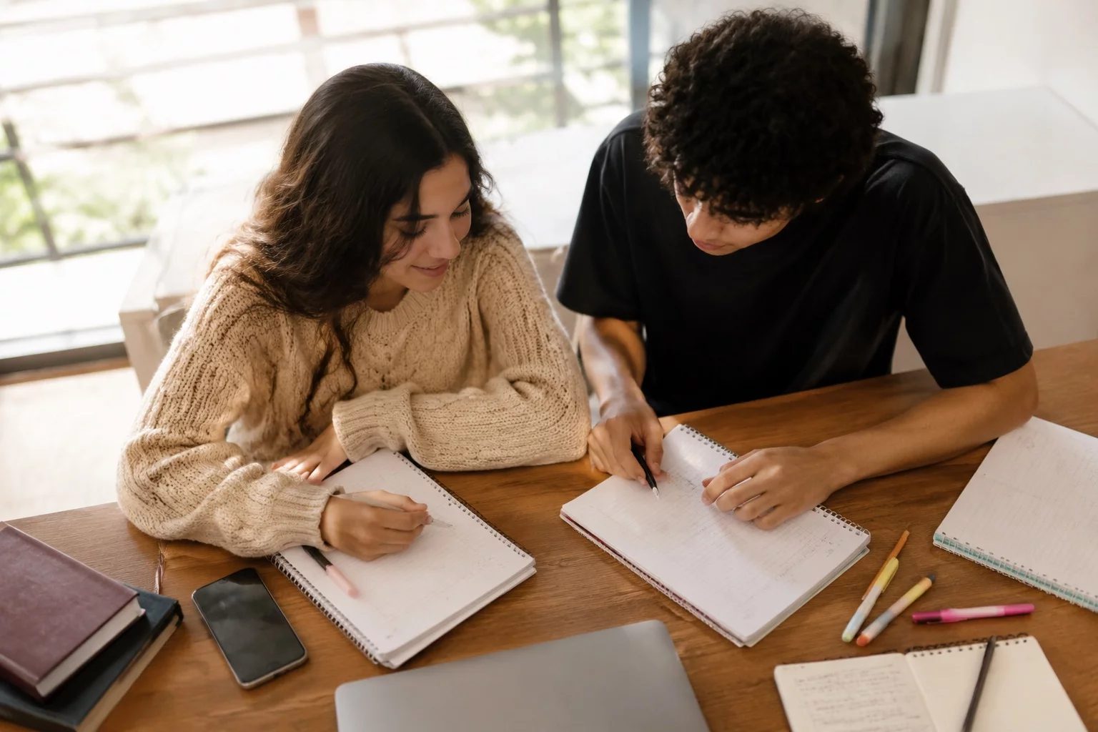 Dois estudantes preparando um debate com cadernos e marcadores