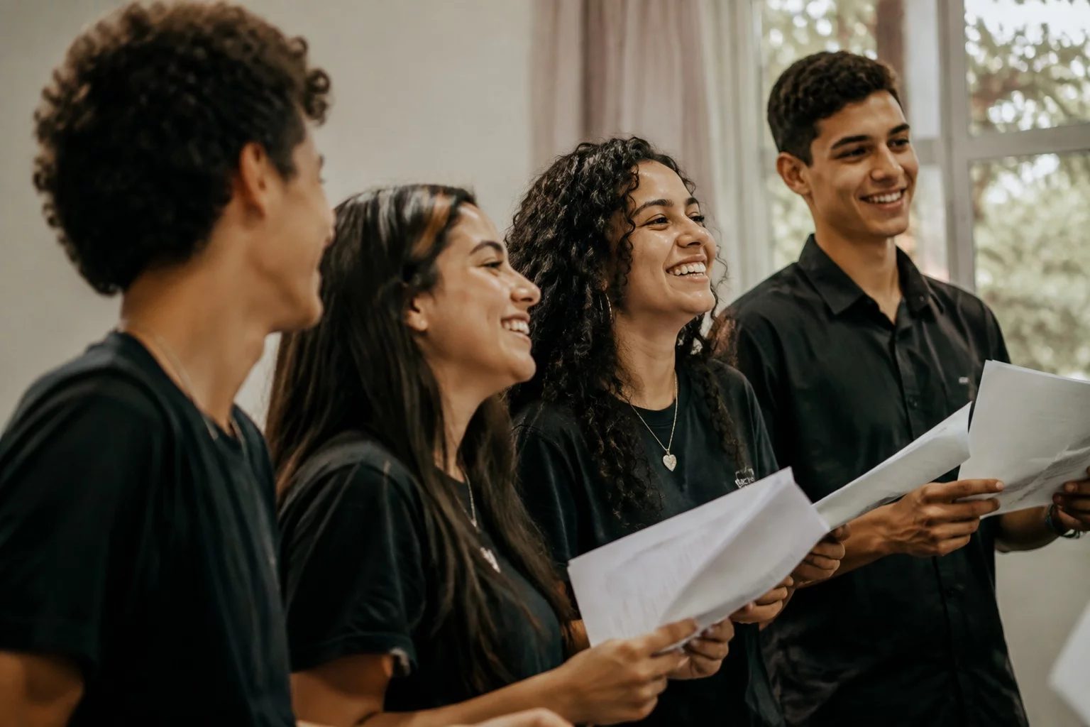 Grupo sorrindo após uma rodada de debate, com papéis nas mãos